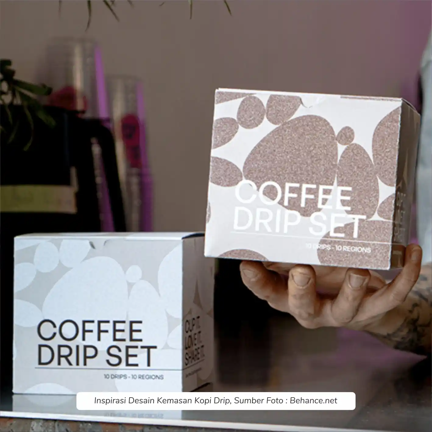 Kemasan kopi Bogor kotak kokoh digenggam tangan permukaan doff bermotif biji terasa hangat tulisan jelas melindungi aroma segar